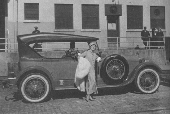 Mae strikes a pose at the studio with one of her automobiles.